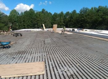 Commercial roof under construction with workers installing insulation on a flat rooftop